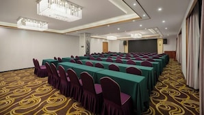 A conference room with rows of tables and chairs, a patterned carpet, and modern lighting fixtures. - Manju Hotel (Shaoxing)