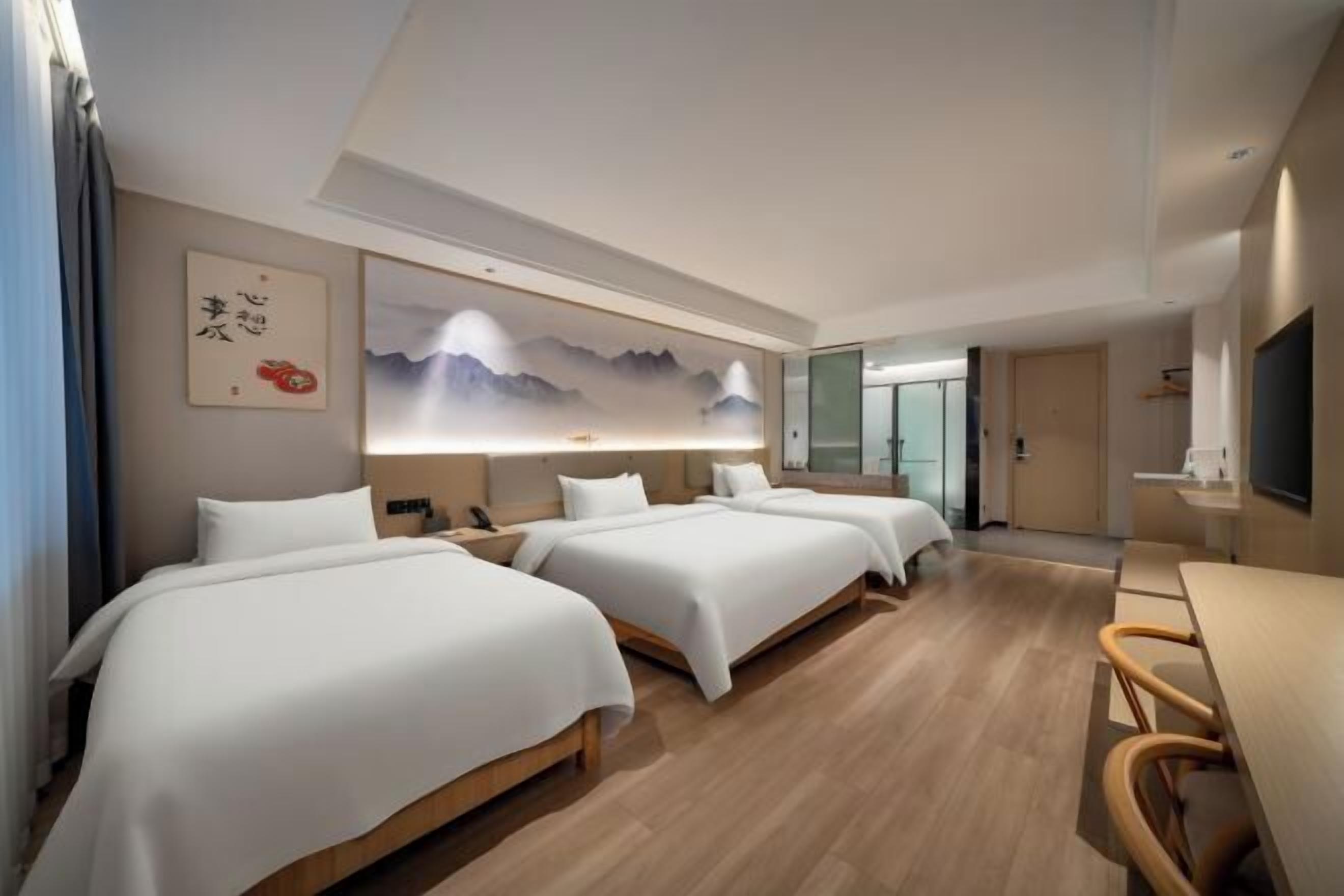 Habitación de hotel con dos camas, un escritorio y un televisor.