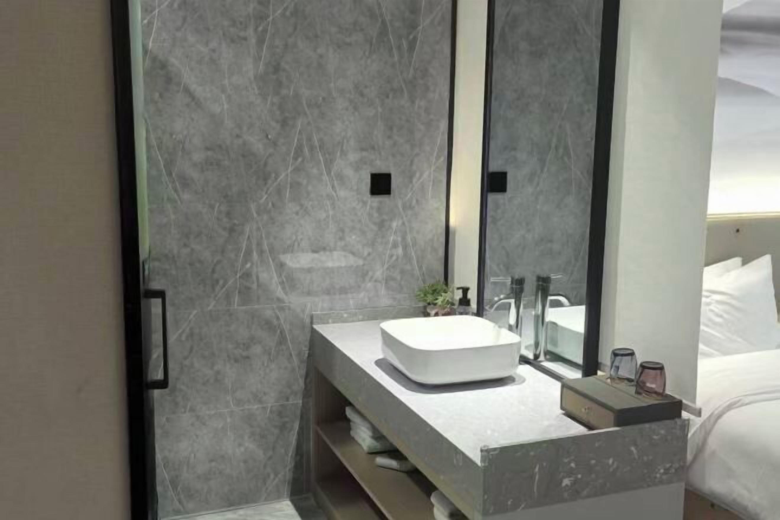 A modern bathroom with a large mirror, a white sink, and a shower area.