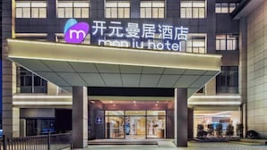 A hotel entrance with a modern facade, large glass doors, and a prominent signage. - Manju Hotel (Shaoxing)