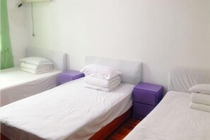 A hotel room with two single beds, each with white bedding and purple nightstands. - Caihong Hostel (Wuyuan)