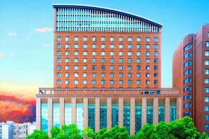 Ein mehrst öckiges Hotel mit gebogener Spitze, großen Fenstern und einem zentralen Eingang.