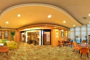 A hotel lobby with a curved ceiling, a reception desk, and seating areas.