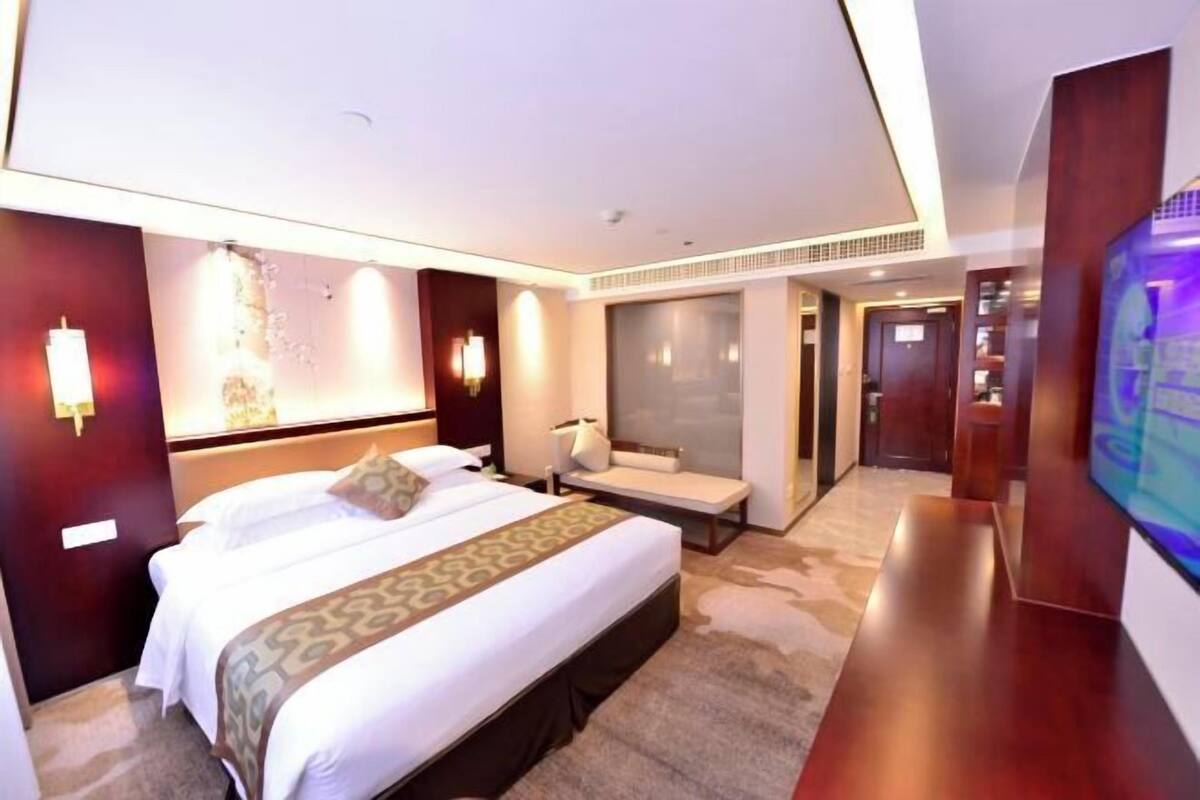 Een hotelkamer met een groot bed, nachtkastjes, een televisie en een zithoek.