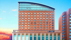 Een hoog hotel met een modern architectonisch ontwerp, gekenmerkt door een gebogen bovenkant en een symmetrische gevel.