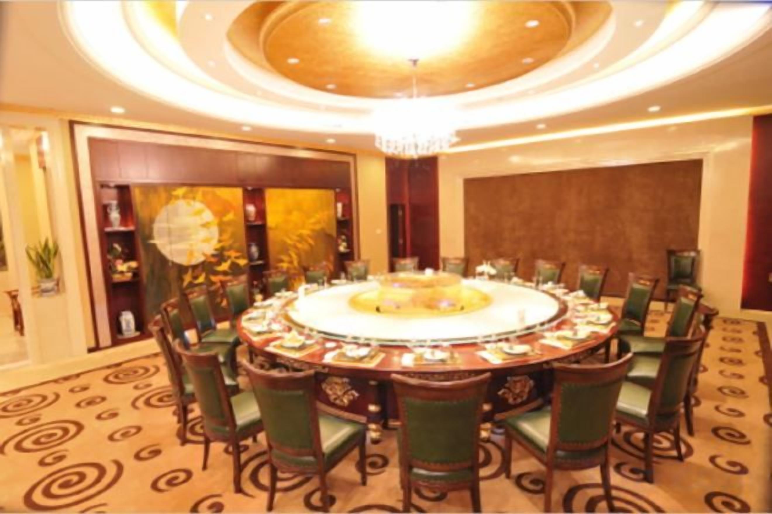 A round table with chairs, a chandelier, and a patterned carpet.