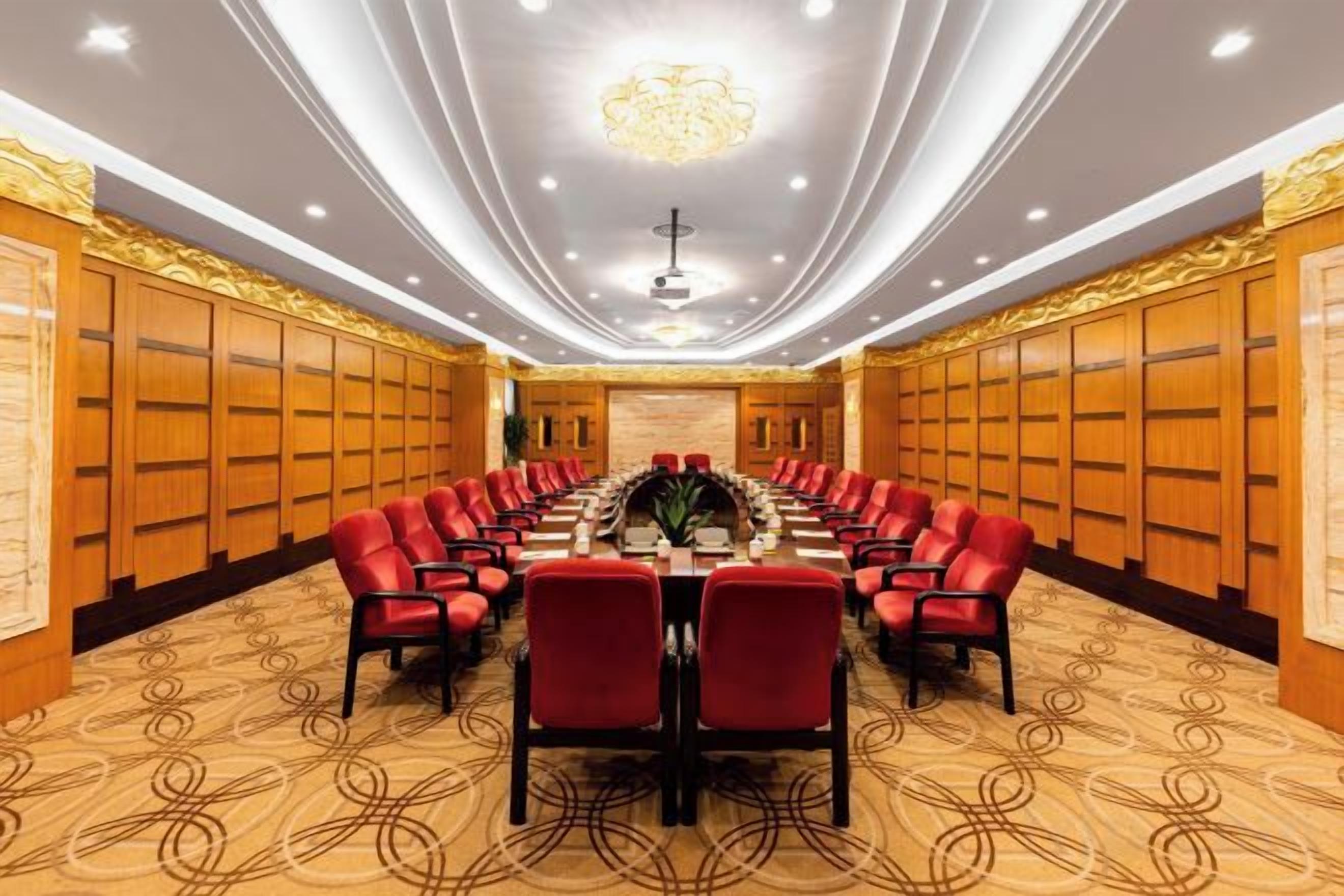 A conference room with a long table, red chairs, and a chandelier.