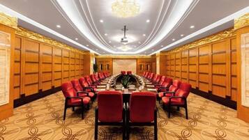 A conference room with a long table, red chairs, and a chandelier.