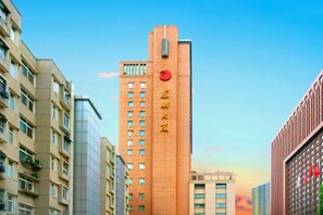 Een hoog gebouw met een rood, cirkelvormig logo en Chinese tekens op de gevel.