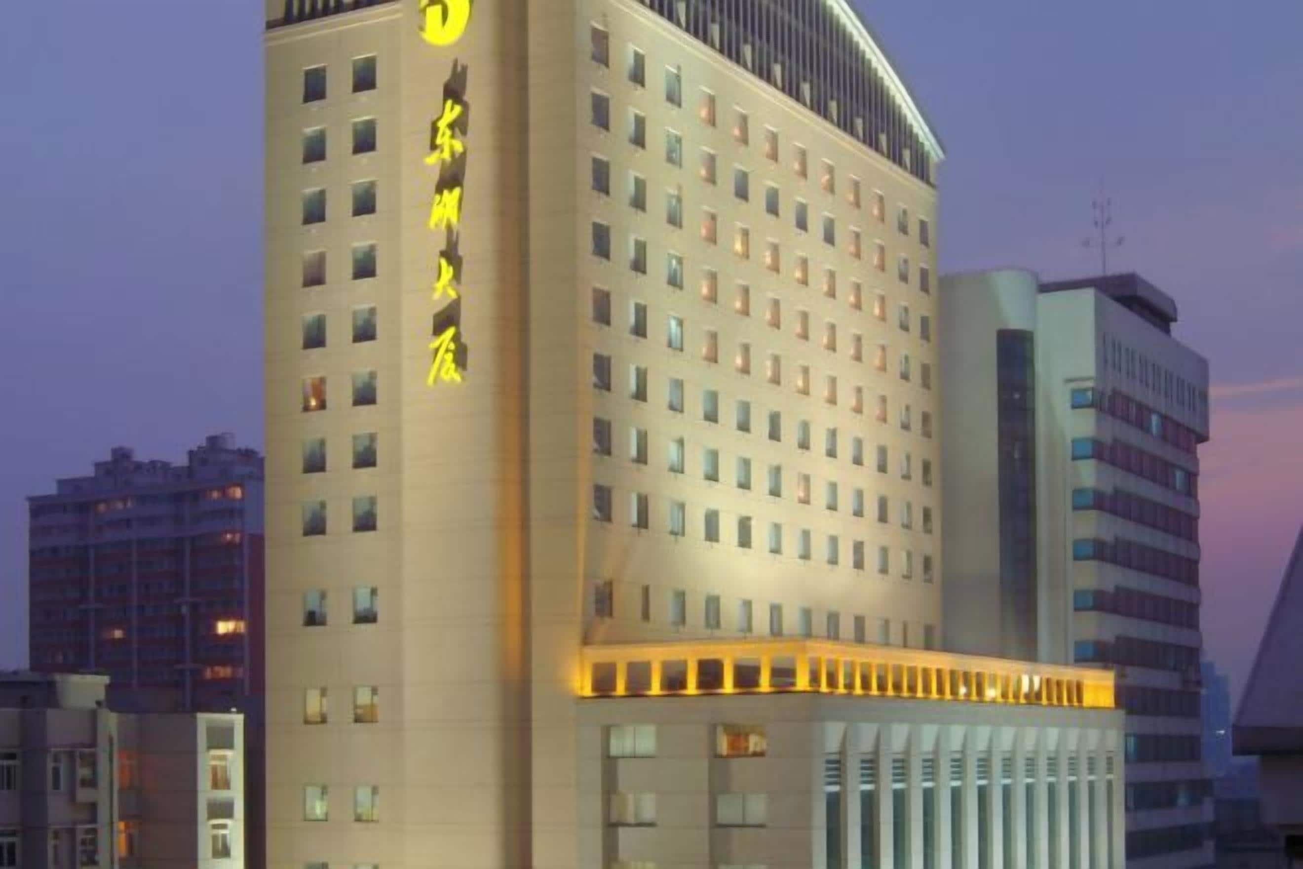 A multi-story hotel with a prominent sign on the facade, featuring a series of windows and a flat roof.