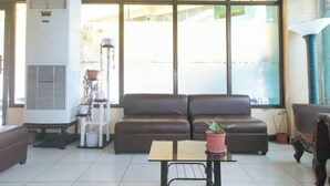 Un espace de vie comprenant un canapé marron, une petite table et une plante en pot.