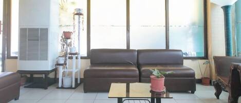 A living room with a brown sofa, a small table, and a potted plant.