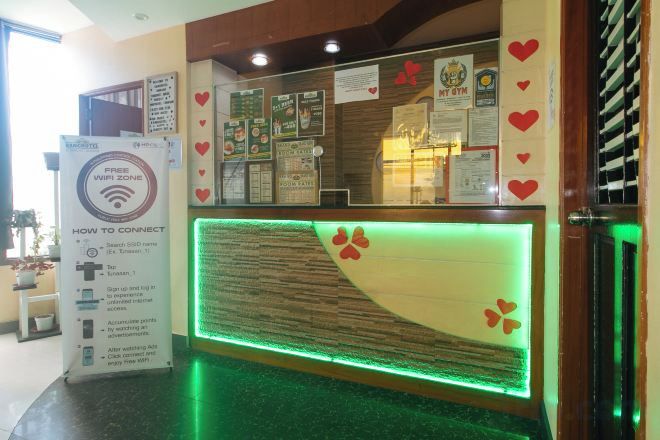 A reception desk with a glass partition, a digital display, and a sign with Wi-Fi information.