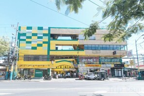 A multi-story building with commercial spaces on the ground floor, including a pharmacy and a cafe. - RedDoorz Near SM City Muntinlupa (Muntinlupa)