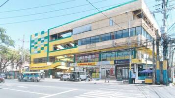 Un edifici de diversos pisos amb una cafeteria a la planta baixa i una farmàcia visible.