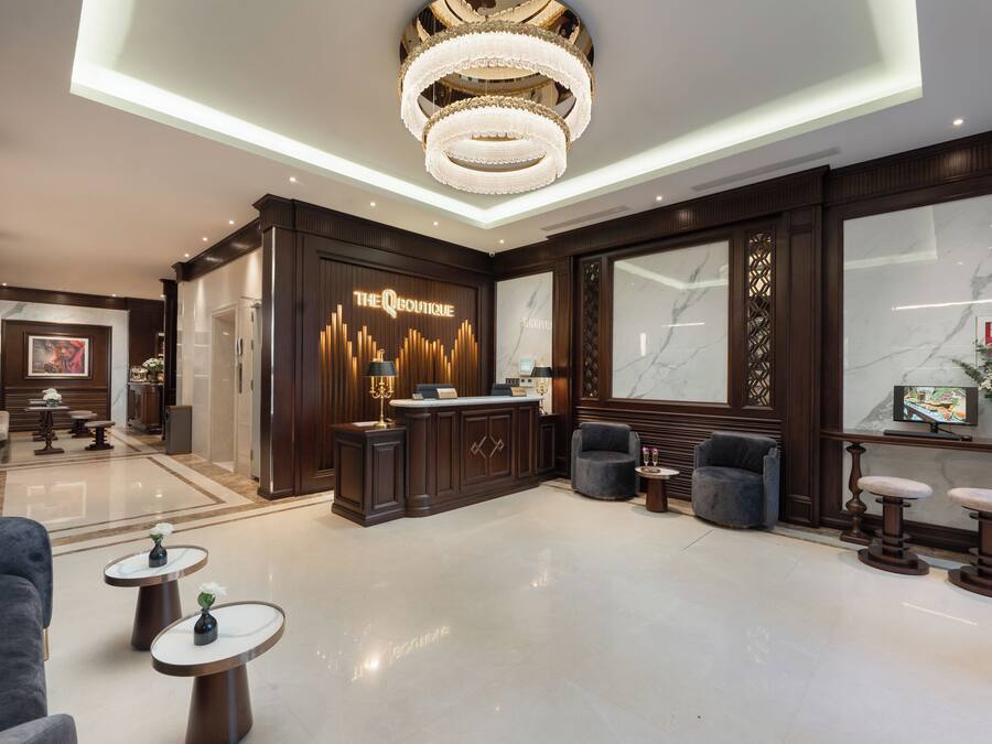 A modern lobby with a reception desk, seating areas, and a chandelier.