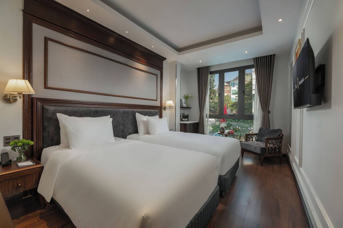 Une chambre d’hôtel avec deux lits, une télévision, un petit balcon et un plancher en bois.