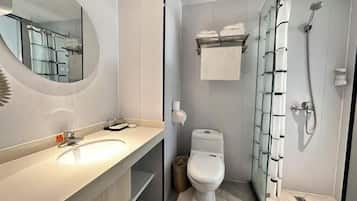 Un baño moderno con un espejo grande, un lavabo, un inodoro y una ducha con mampara de vidrio.