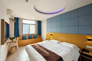 Habitación de hotel con cama, escritorio con silla, ventana con cortinas y televisor de pared.