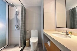 Un baño moderno con cabina de ducha de vidrio, inodoro y lavamanos con espejo.
