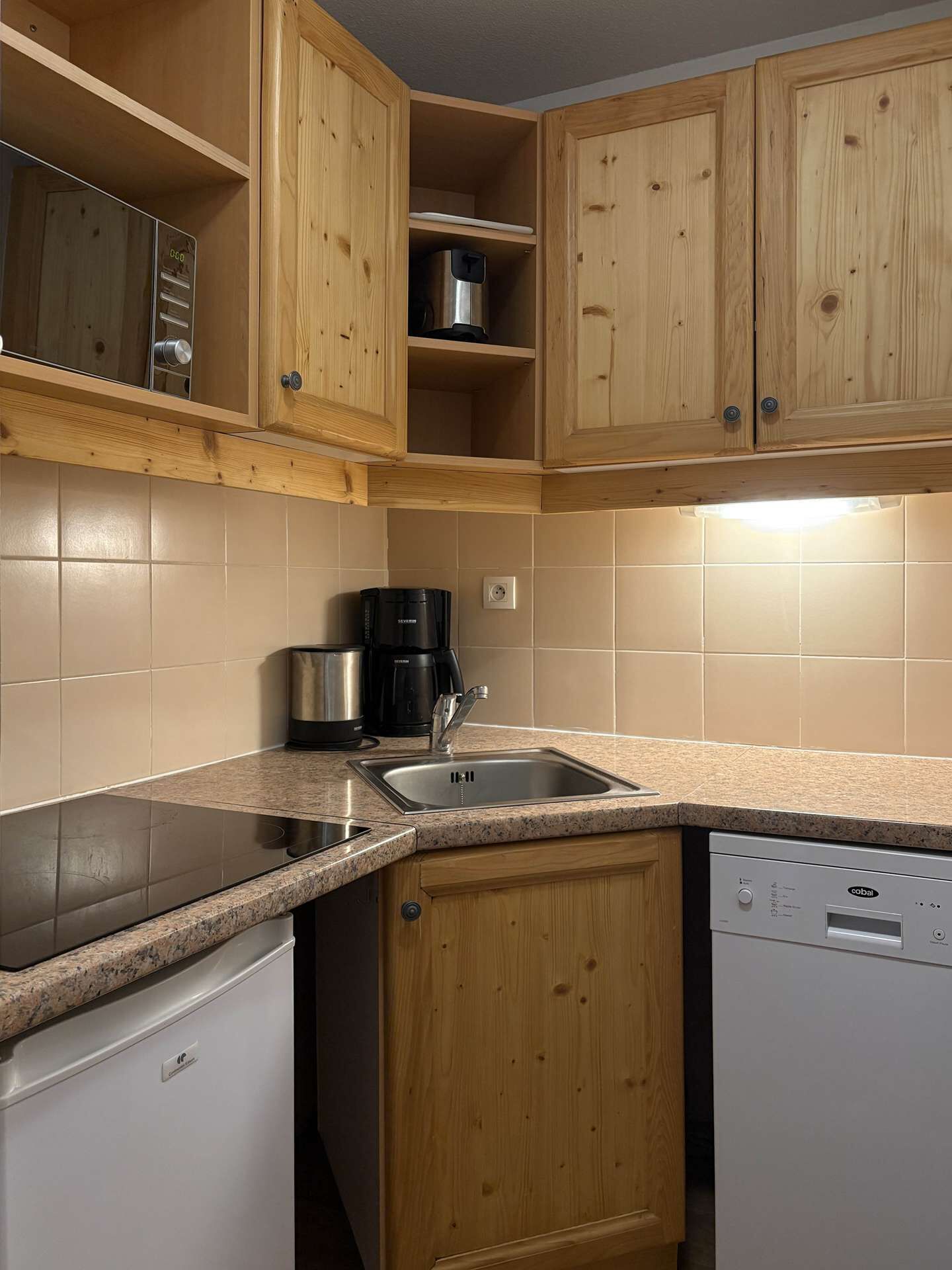 A kitchen with wooden cabinets, a stainless steel sink, a coffee maker, and a dishwasher.