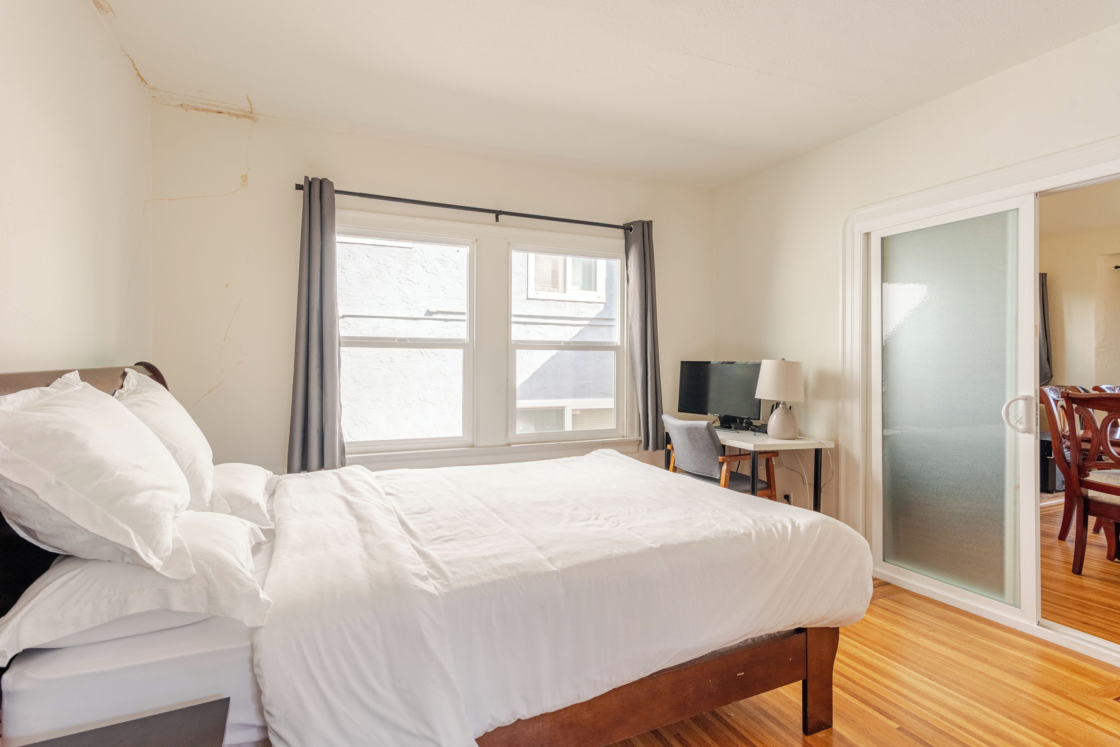A bedroom with a bed, a desk, a chair, and a TV.