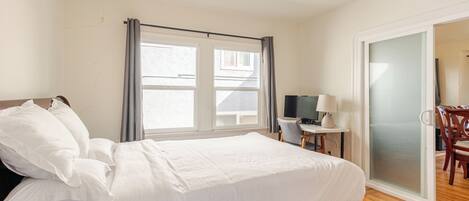 A bedroom with a bed, a desk, a chair, and a TV.