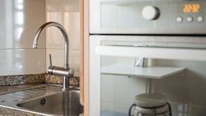 A kitchen with a stainless steel sink, a modern faucet, and a built-in oven.
