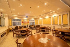 A conference room with multiple tables and chairs, a fireplace, and framed artwork on the walls. - Ming Fan Ju Hotel (Ruili)