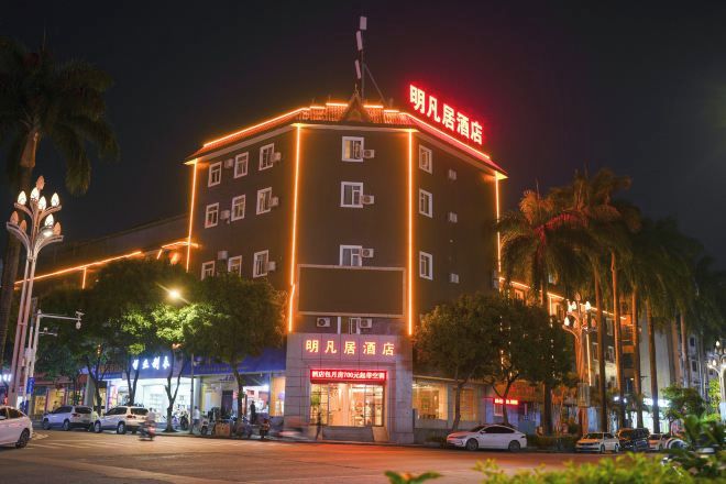 A multi-story hotel with illuminated signage, a ground-level restaurant, and a parking area with cars.