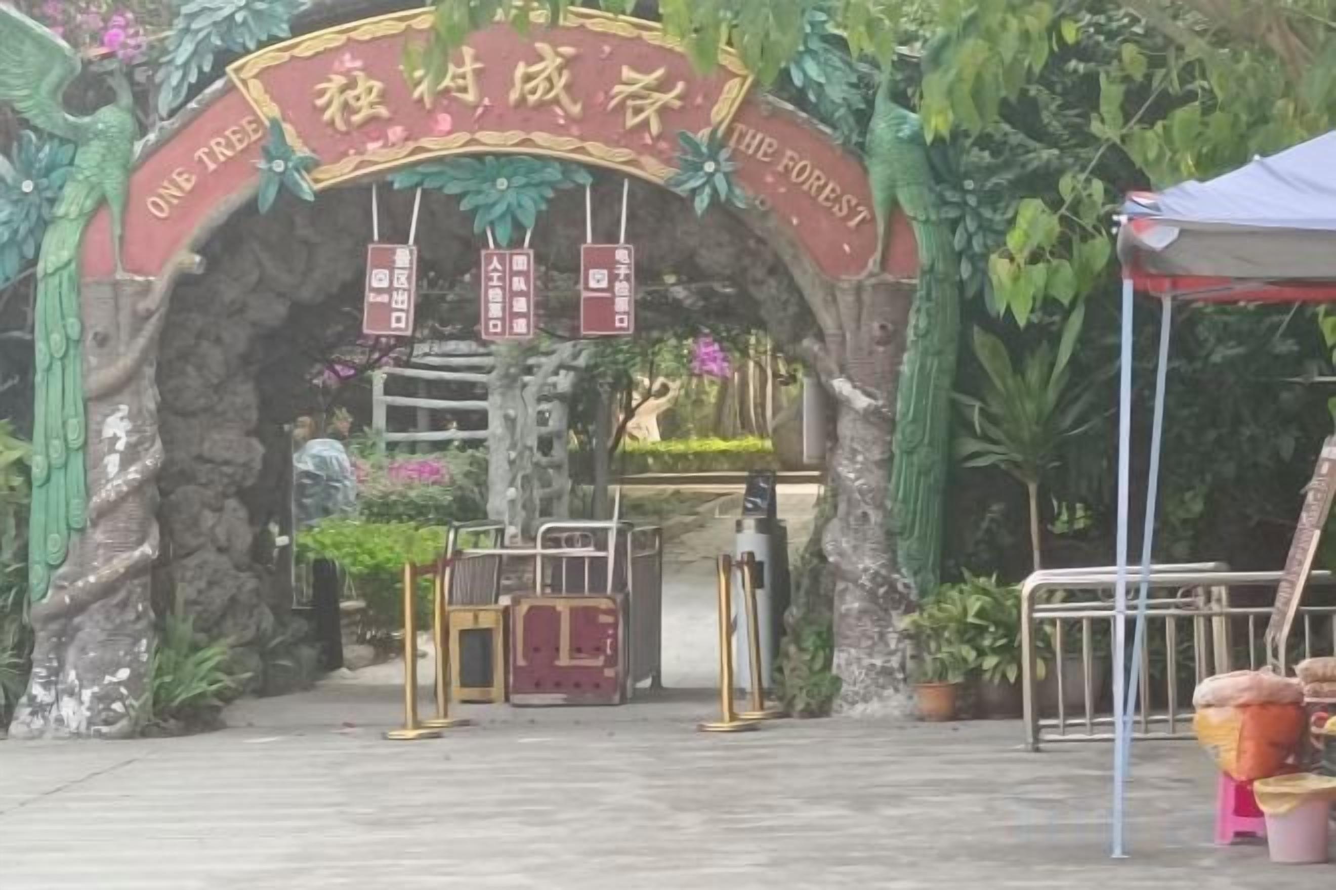 Una entrada con un letrero que dice 'ONE TREE THE FOREST' y una puerta.