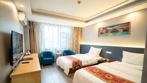 Une chambre d’hôtel avec deux lits, un bureau avec une télévision, une chaise, une fenêtre avec des rideaux et un tableau au mur.