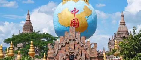 A large golden globe with Chinese characters, surrounded by traditional architecture and a clear sky.