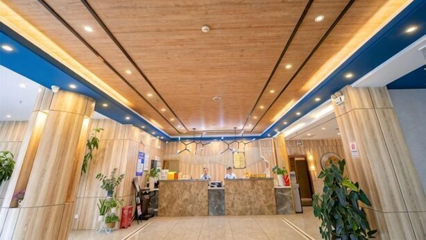 Un hall d’hôtel avec un plafond en bois, un comptoir d’accueil et des plantes en pot.