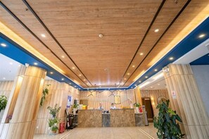 Un hall de hotel con techo de madera, una recepción y plantas en macetas.