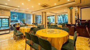 Un restaurant avec des tables rondes, des chaises, un bar et de grandes fenêtres.