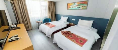 A hotel room with two beds, a desk, a chair, and a small table.