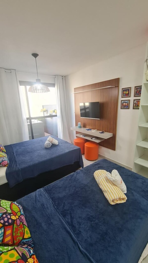 A hotel room with two beds, a TV, and a window with curtains. - Flat Ofurô 08 VP by La Playa (Ipojuca)