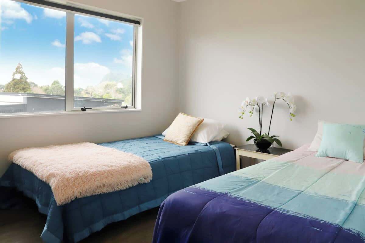 Ein Schlafzimmer mit zwei Betten, einem Fenster und einer Pflanze.
