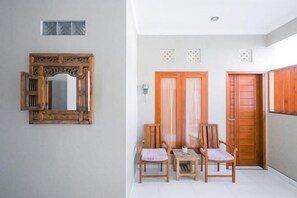 A hallway with a wooden door, a mirror, and two chairs. - RedDoorz near Mertasari Beach 2 (Bali)