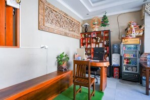 Une pièce comprenant un banc en bois, un bureau avec un ordinateur, une bibliothèque, un réfrigérateur et un élément décoratif mural.