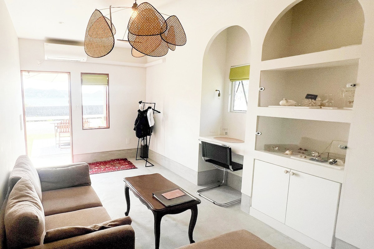 A modern living room with a sofa, a coffee table, and a kitchen area with a sink and cabinets.