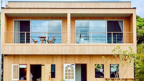 A two-story wooden building with large windows and a balcony. - HOLLY CAMP CASA (Amami)