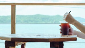 A wooden table with a clear view of a body of water and mountains in the background. - HOLLY CAMP CASA (Amami)