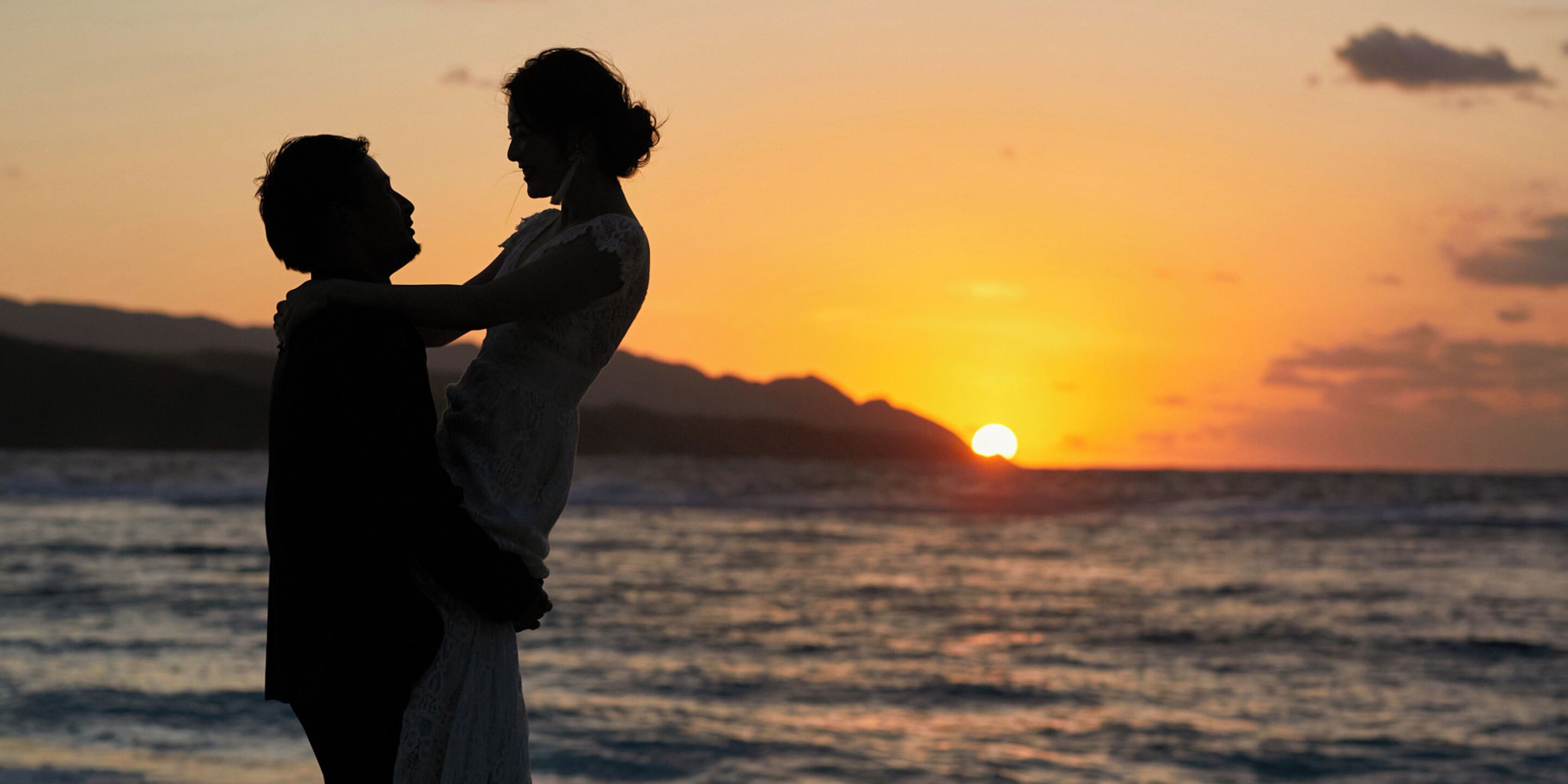 Silueta de una pareja abrazándose al atardecer sobre el océano.