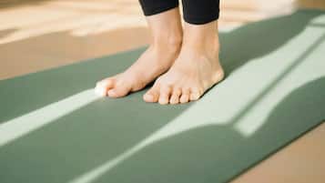 A pair of feet standing on a green exercise mat.