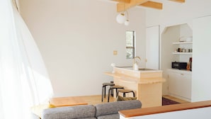 A modern, compact living space with a kitchen area, a dining table, and a sofa. - HOLLY CAMP CASA (Amami)