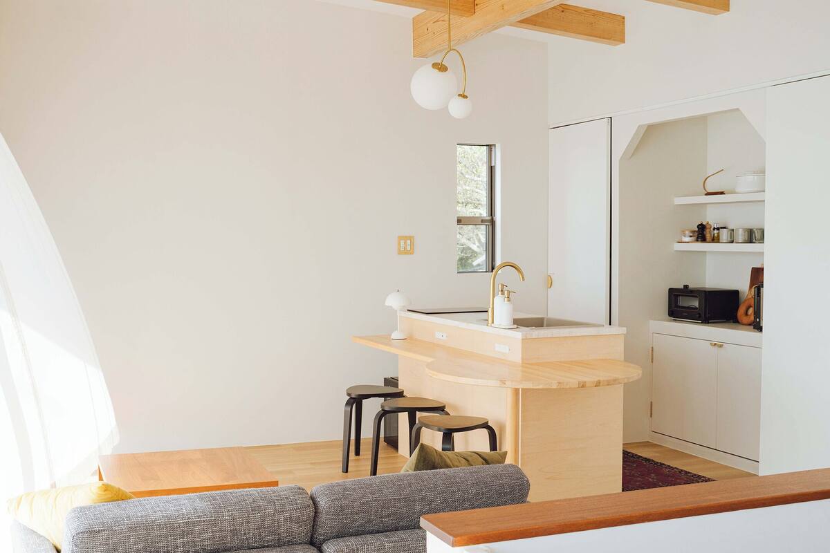 A modern, compact living space with a kitchen area, a dining table, and a sofa.