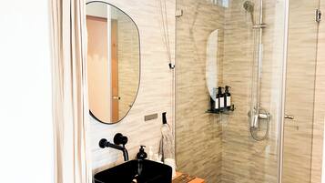 Een moderne badkamer met een zwart wastafel, een spiegel, een douche en een toilet.