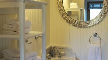 Une salle de bain avec un meuble-lavabo blanc, un évier et un miroir orné d’un cadre en mosaïque.